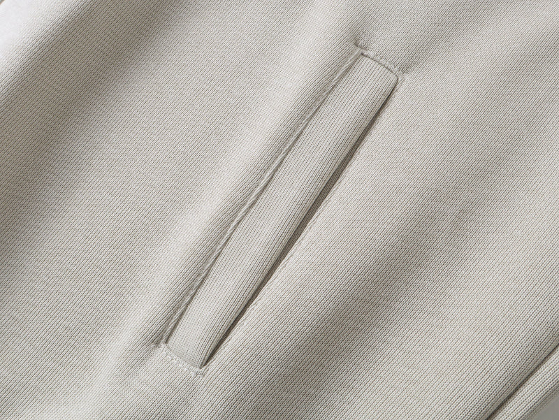 Close-up of beige hoodie front pocket opening and ribbed trim