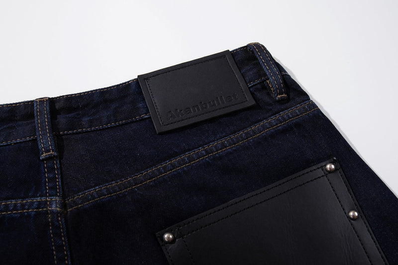 Close-up of the back waistband patch and belt loop on deep indigo jeans