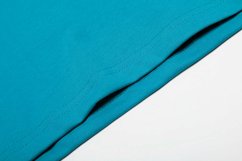Close-up of teal athletic T-shirt fabric with clean stitched hem and color block edge