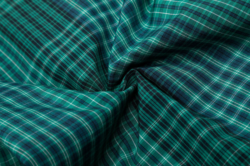 Close-up of green plaid fabric with gathered fold and soft texture