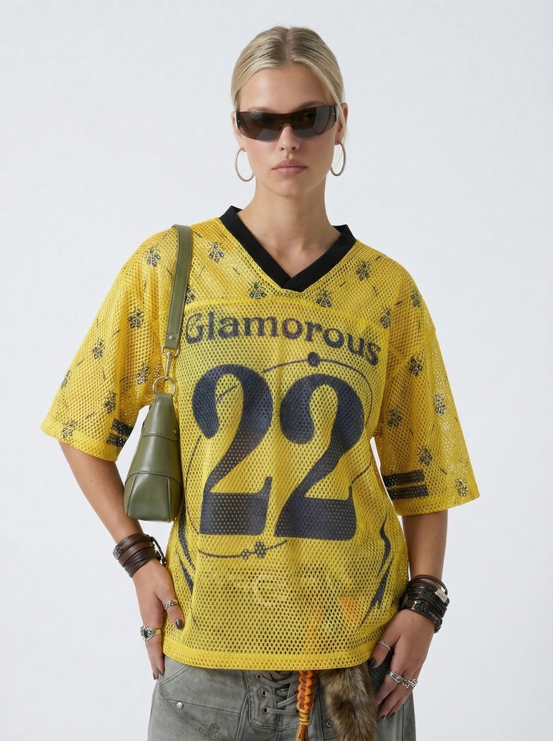 Model wearing a yellow mesh jersey T-shirt with number 22, black V-neck trim, and streetwear styling with sunglasses and hoop earrings