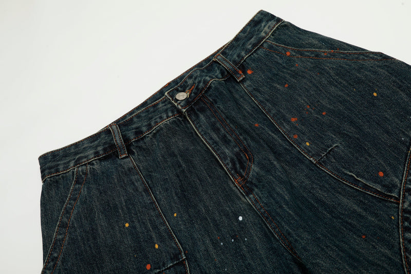 Close-up of the waistband and front pocket on dark wash paint-splatter jeans