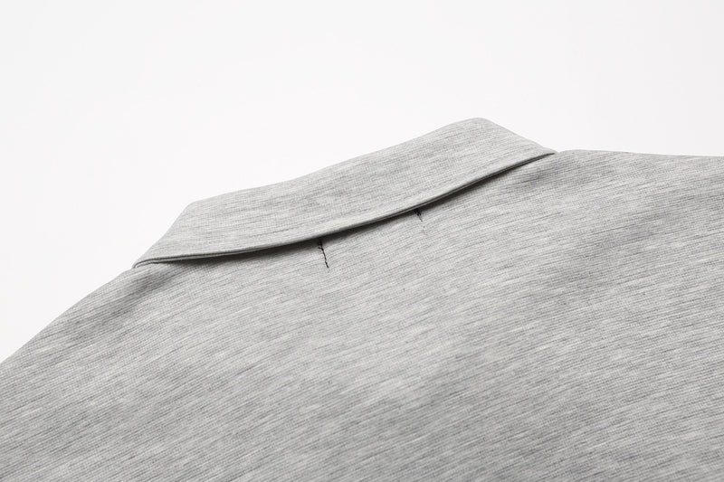 Close-up of a light gray embroidered polo shirt collar with subtle gothic detailing and soft cotton texture