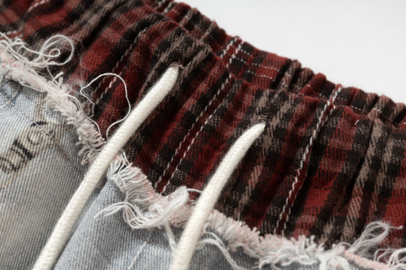 Close-up of red-and-black plaid waistband with frayed seam and white drawstrings