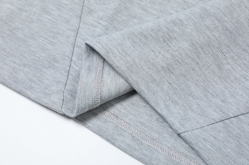 Close-up of a light gray oversized tee hem with geometric seam detailing and clean structured stitching