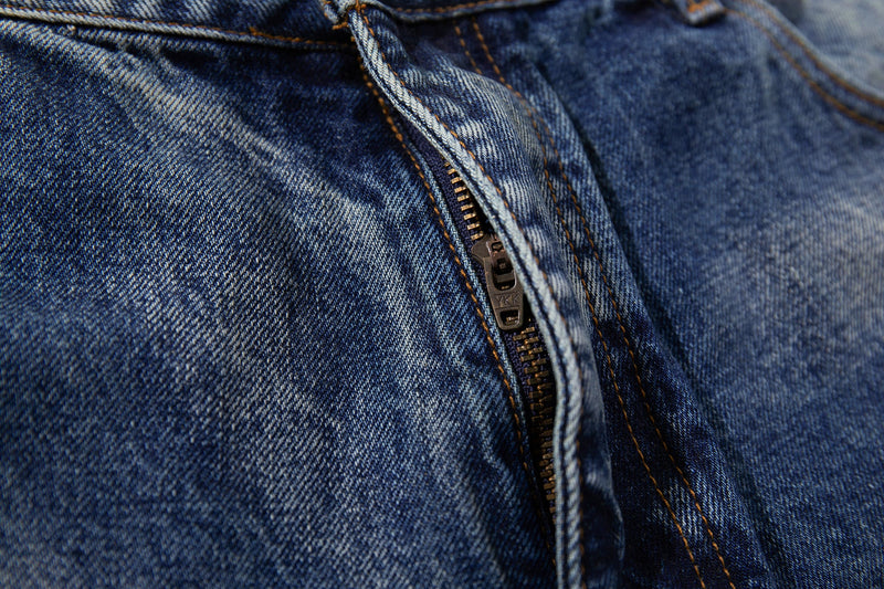 Close-up of denim zipper fly with heavy fade and orange topstitching