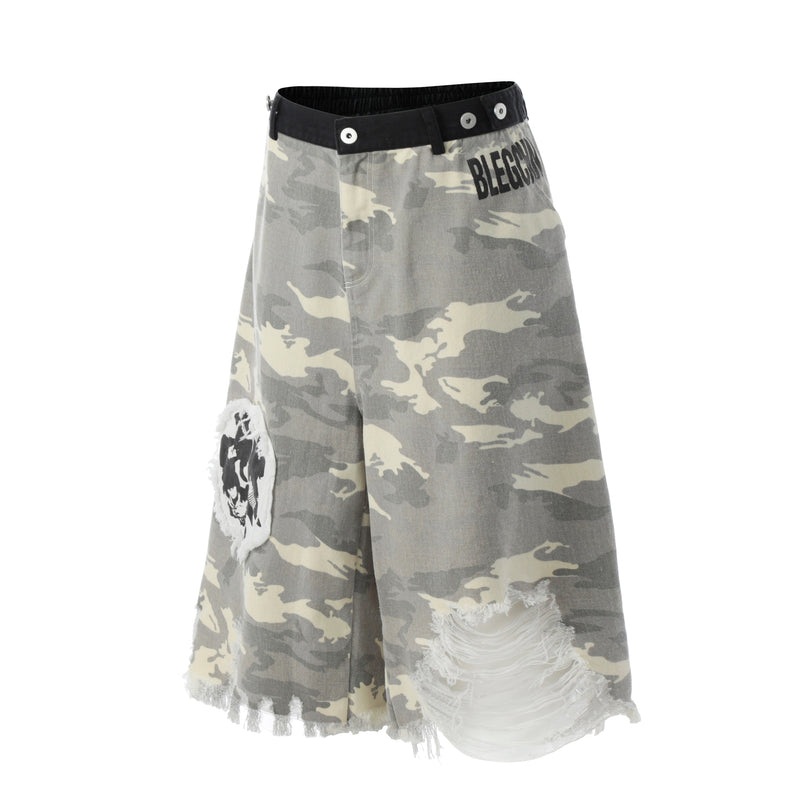 Front angled view of gray camo jorts showing black waist trim, printed logo, and distressed patch