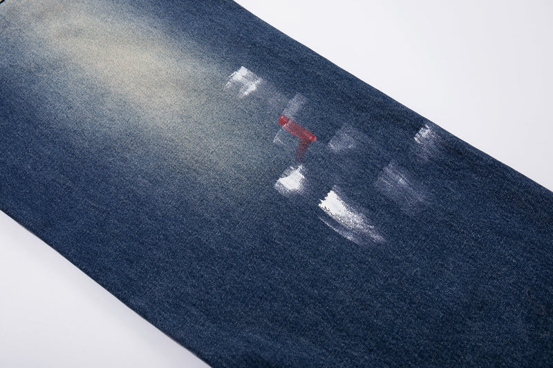 Close-up of brushstroke paint splatter on blue denim pant leg