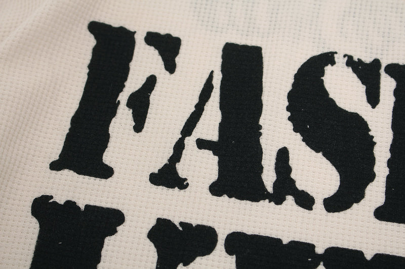 Close-up of the Fashion Killa lettering printed in black on cream waffle knit fabric