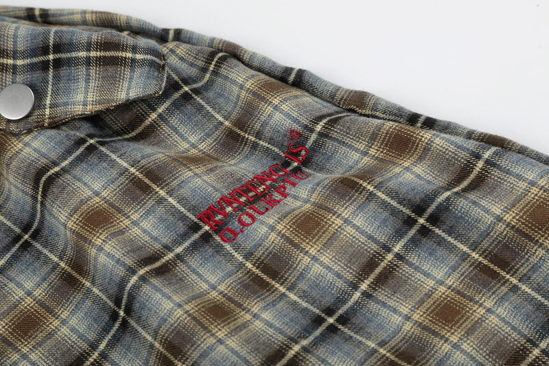 Close-up of red embroidered text on blue-brown plaid lounge shorts