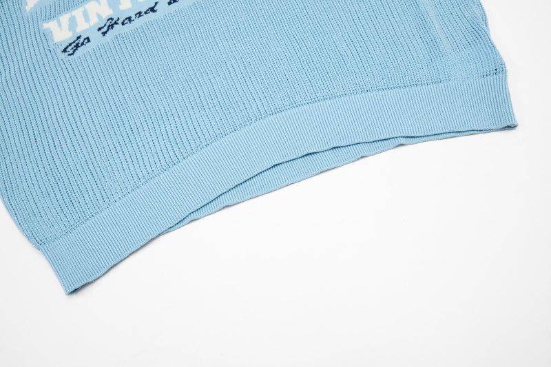 Light blue knit polo hem with ribbed trim and collegiate logo detail on a clean white background