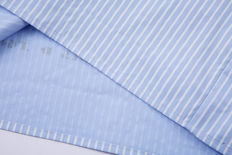Close-up of striped shirt hem layered over lighter blue underlayer