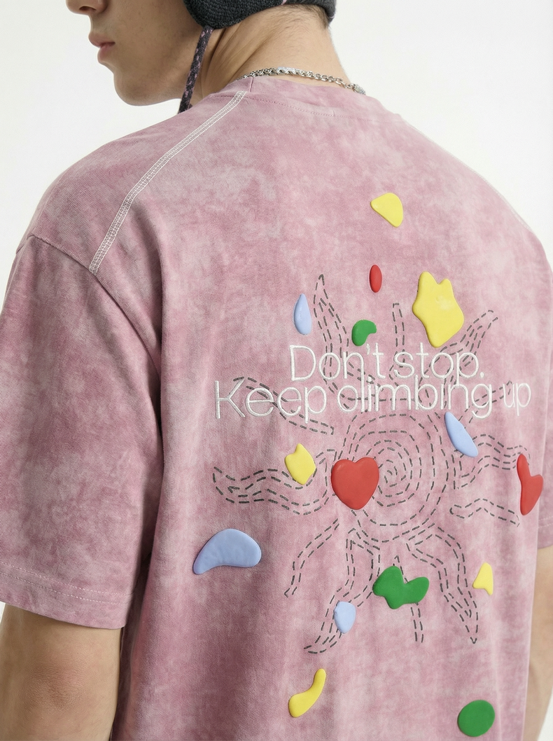 Back view of a vintage wash pink graphic tee with colorful climbing-inspired print and Keep Climbing text