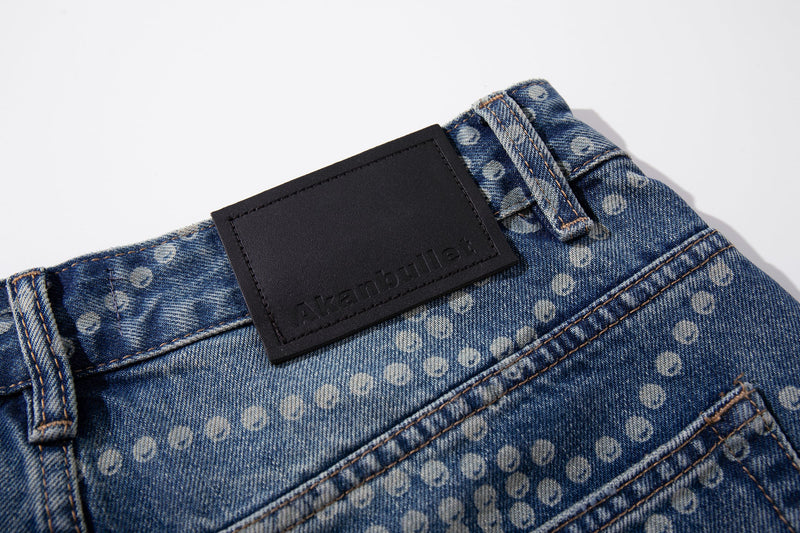 Close-up of black back waist label on faded blue dot-pattern jeans