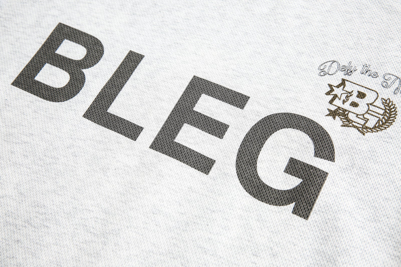 Close-up of BLEG chest print and crest graphic on off-white fabric
