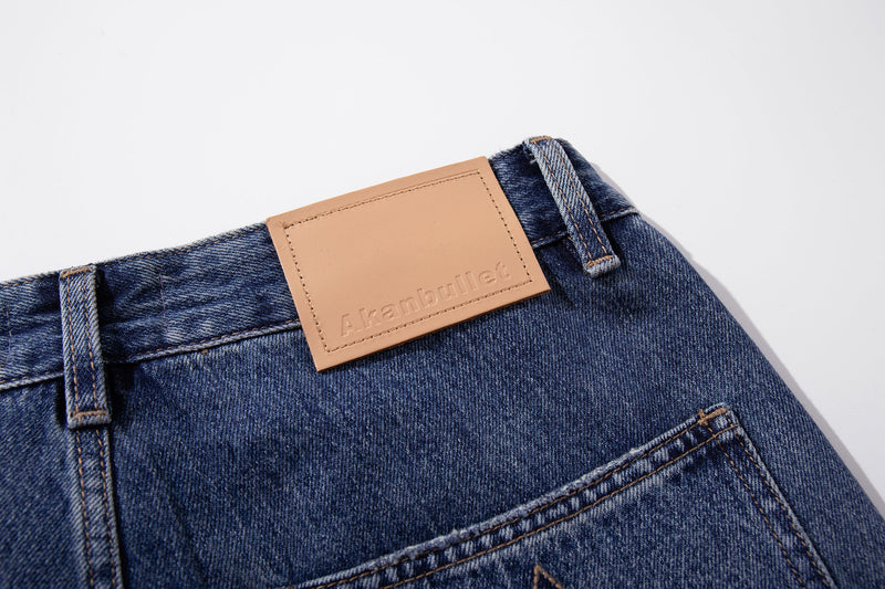 Close-up of tan leather back patch and belt loops on blue denim jeans