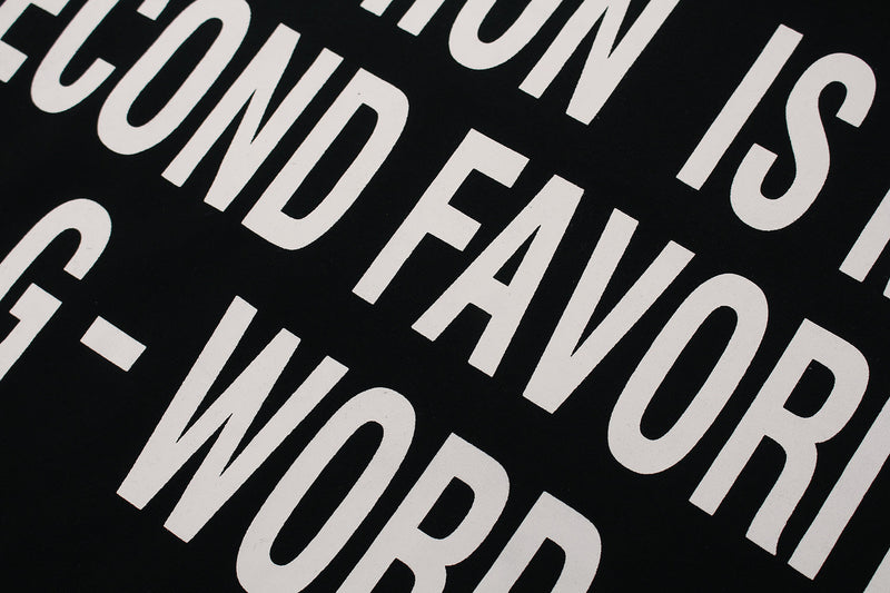 Close-up of black oversized tee with bold white slogan print in diagonal streetwear style