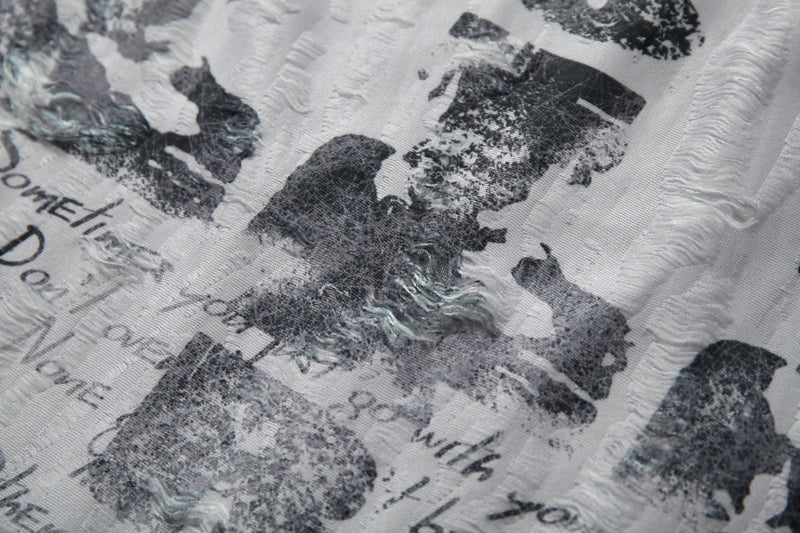 Close-up of white distressed graphic mesh tee with black abstract print and textured patchwork detailing