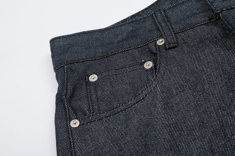 Close-up of front waistband, button fly, and pocket detail on dark wash denim jorts