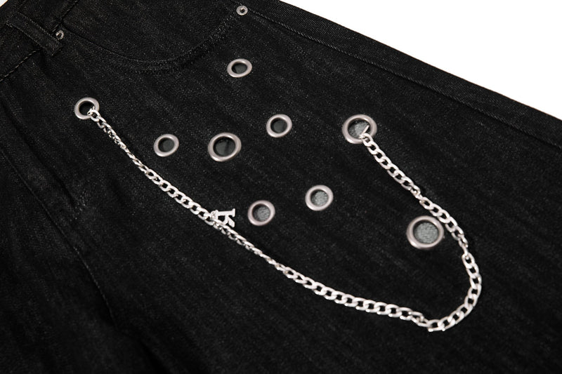 Close-up of front panel on black denim pants with eyelets and silver chain