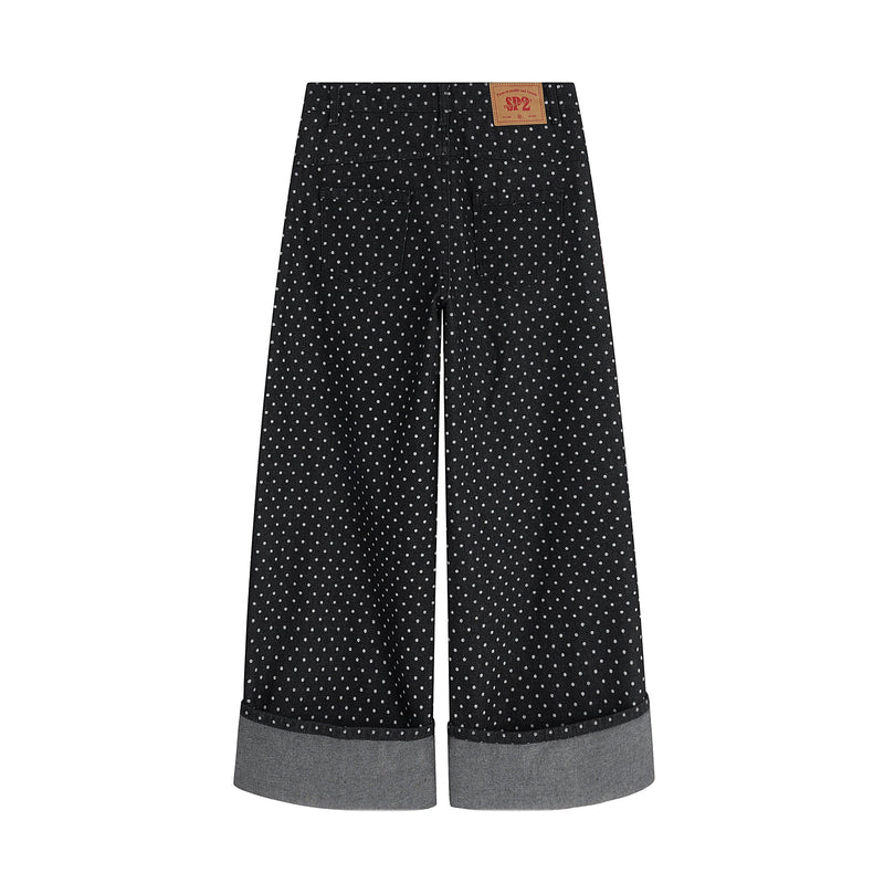 Back view of black polka-dot wide-leg denim pants with turn-up cuffs and back pockets