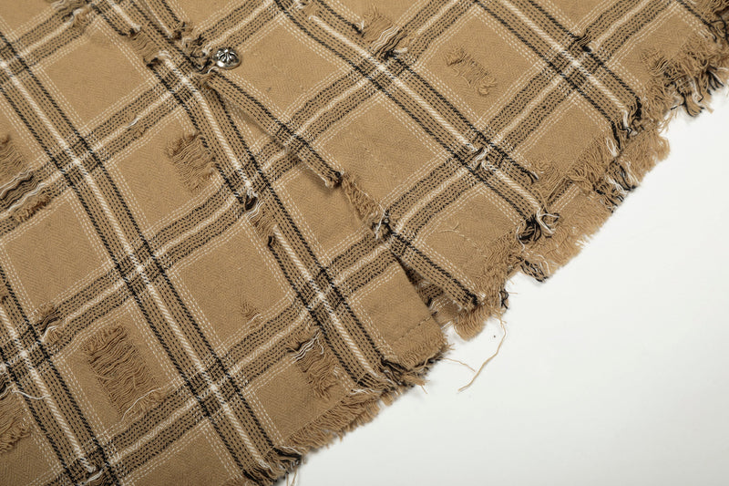 Close-up of tan plaid overshirt hem showing frayed edge and worn texture