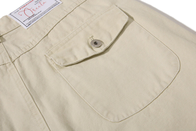 Close-up of beige cargo pant rear pocket with buttoned flap