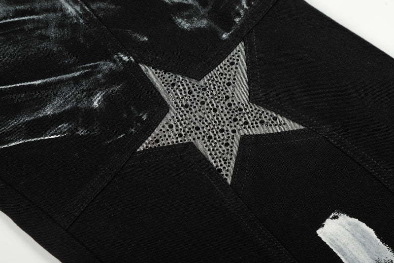 Close-up of star patch on black jeans with dotted silver detail and stitched edges