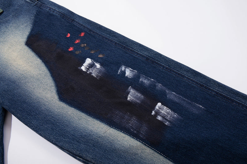 Close-up of painted splatter detail on dark blue jeans leg
