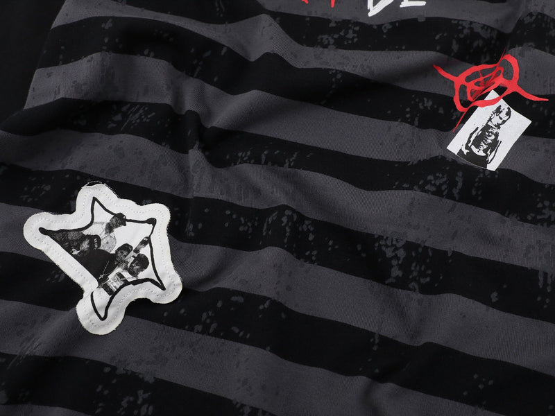 Close-up of black striped tee front with star patch and small red graphic patch