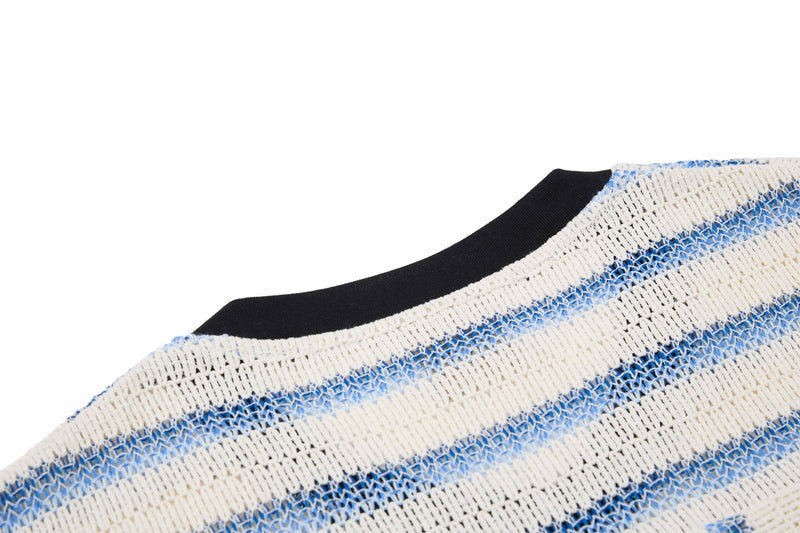 Close-up of a black knit tee with cream and blue varsity stripes on the neckline and fabric