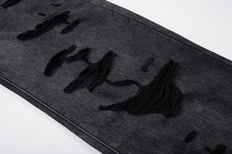 Close-up of distressed leg on deep charcoal jeans with ripped holes and frayed edges