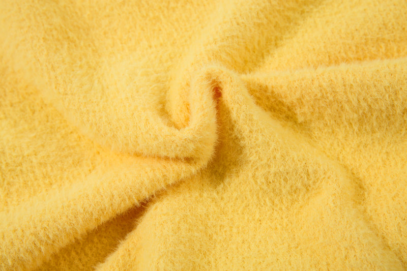 Close-up of yellow fuzzy knit sweater fabric and seams