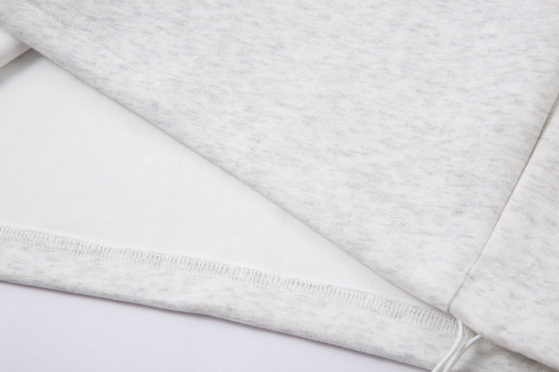 Close-up of the light gray jacket hem with stitched seam and ribbed edge