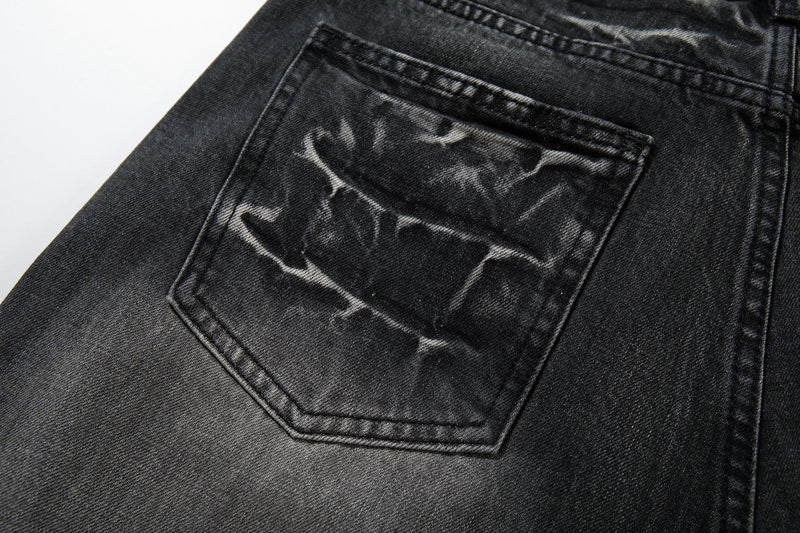 Close-up of one back pocket on black denim jeans with white cracked-wash markings