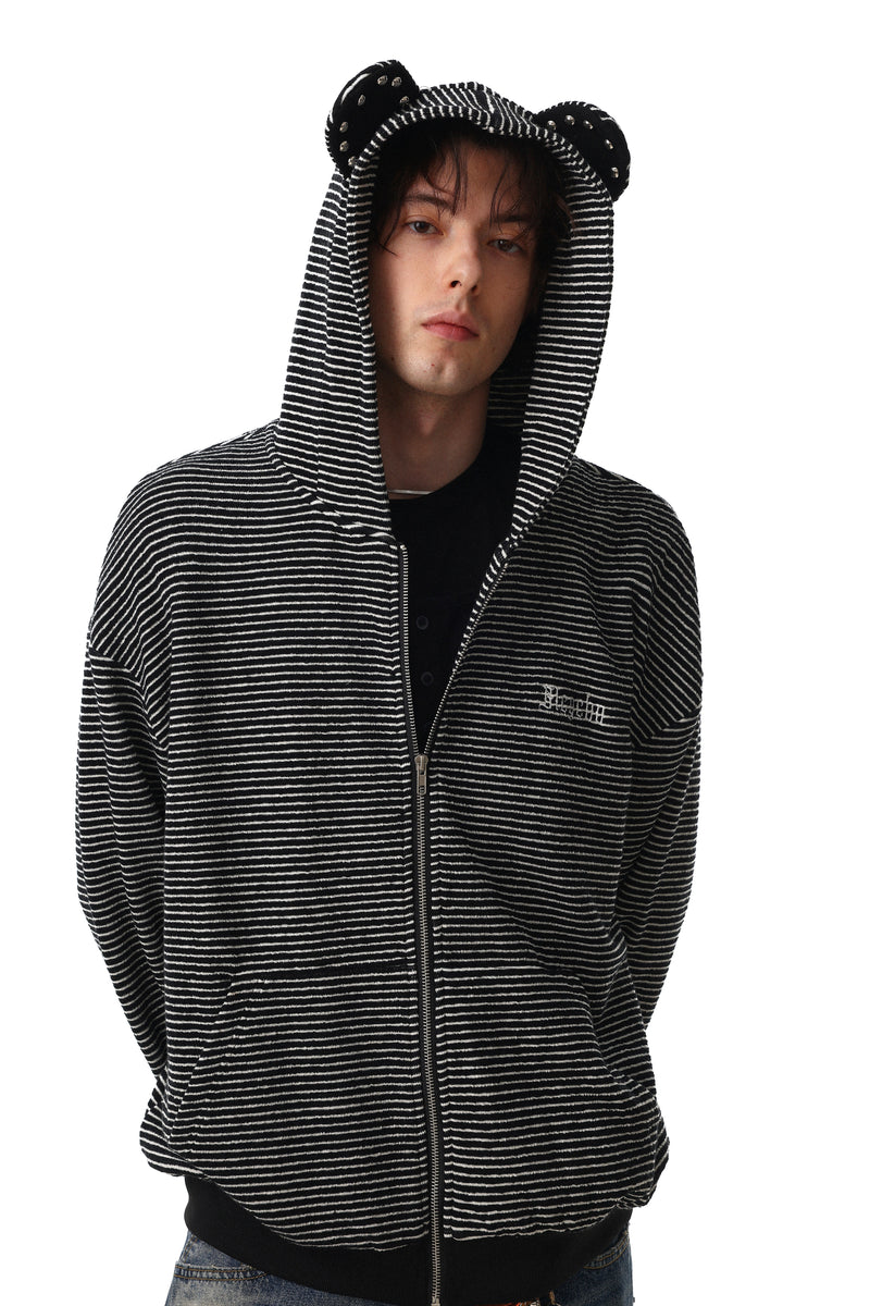 Model wearing black striped zip hoodie with hood up and studded bear ears