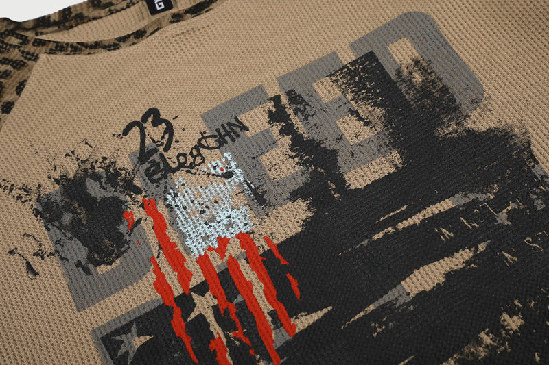 Close-up of tan graphic print on waffle knit shirt with red and black distressed details