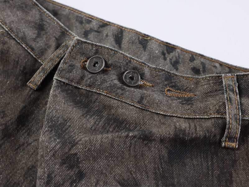 Close-up of waistband buttons and stitched front panel on dark washed denim jeans
