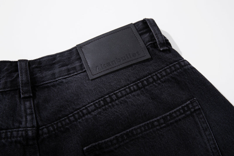 Close-up of back waistband on dark wash jeans with black logo patch