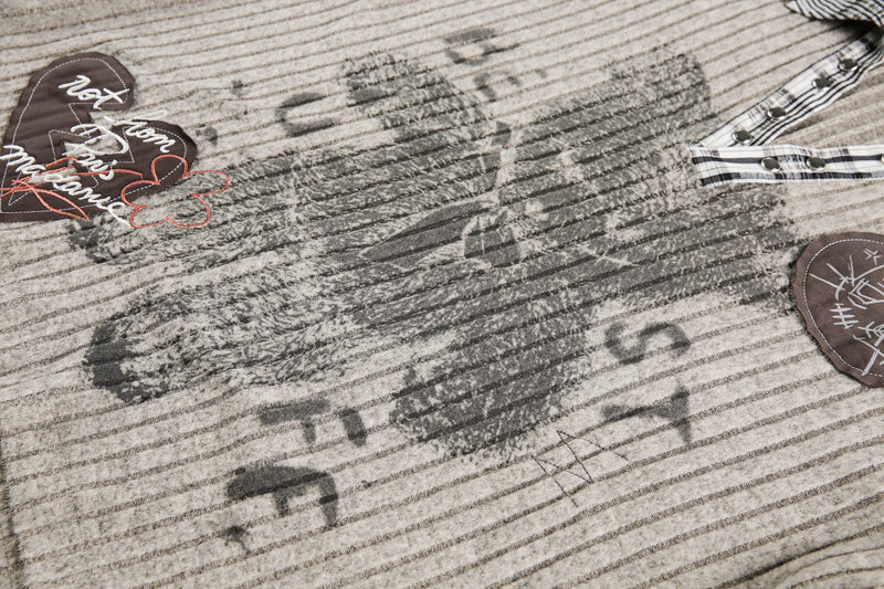 Close-up of beige bear graphic print and patch details on ribbed knit sweater