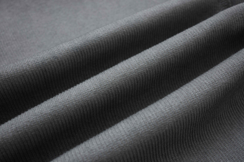 Close-up of gray ribbed compression tee fabric with deconstructed draped folds and textured knit detail