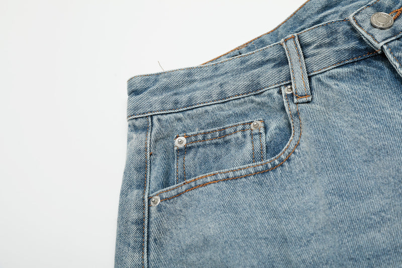 Close-up of front pocket and waistband on light blue distressed denim shorts
