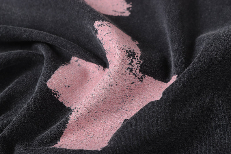 Close-up of pink cross print on black vintage wash tee fabric