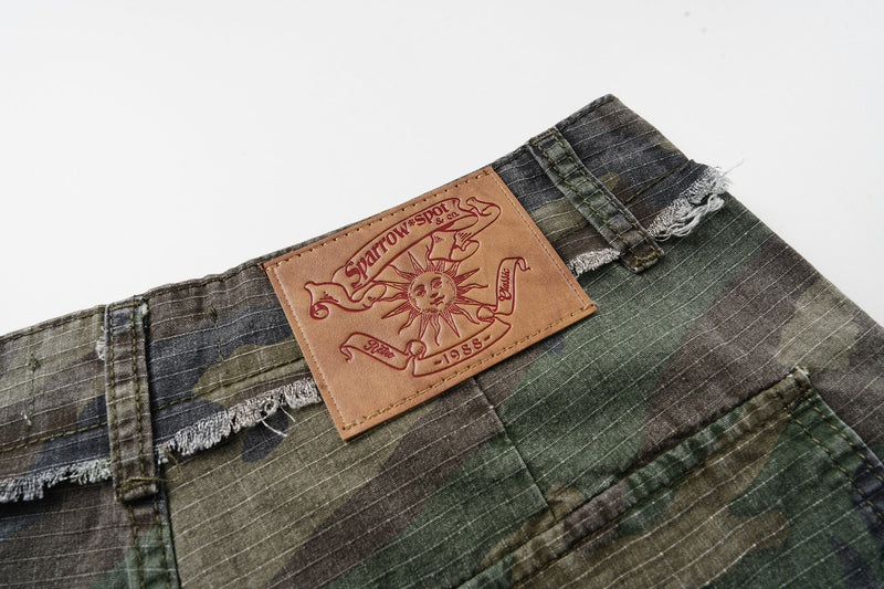 Close-up of the back waistband logo patch with frayed trim and camo fabric