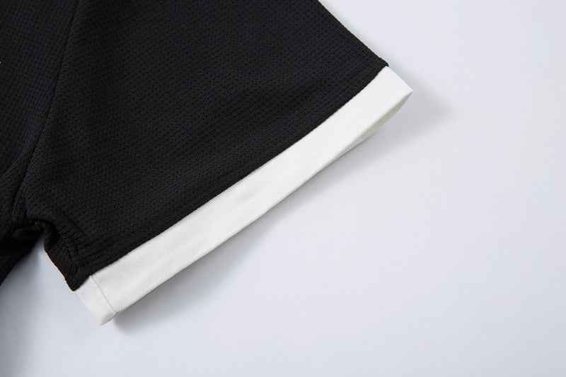 Black textured polo shirt sleeve with crisp white cuff, styled in a dark gothic streetwear look