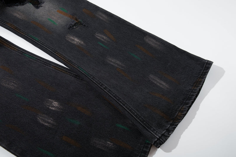 Close-up of the lower leg hem on washed black jeans with painted streaks