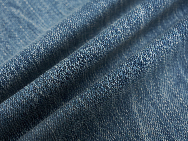 Close-up of blue denim fabric with visible woven texture and soft folded creases