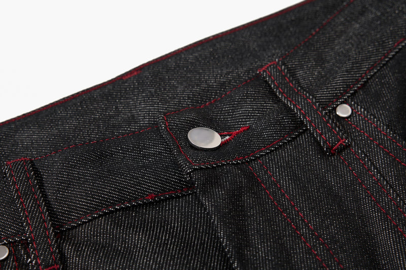 Close-up of black denim waistband button and stitching detail