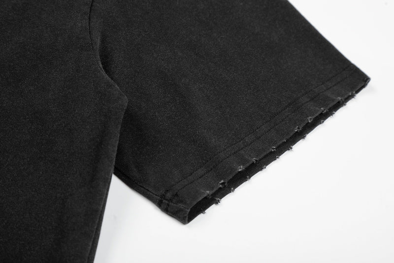 Close-up of a black vintage washed graphic T-shirt sleeve with raw frayed hem stitching on a white background