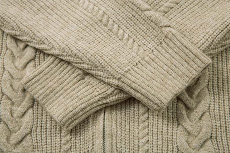 Beige cable knit jacket sleeves crossed, showing ribbed cuffs and textured knit